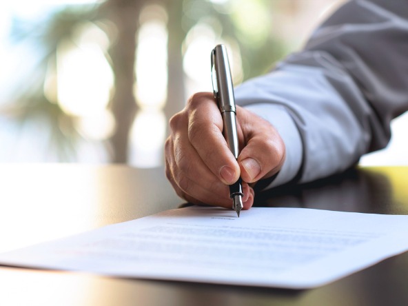 man holding a pen signs a piece of paper